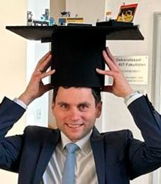 Person mit Doktorhut beim Hochschulabschluss, Händen hebt Kappe über Kopf; Fehldruck/Blurred Face.